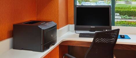 Un escritorio moderno con una impresora, una computadora portátil y una silla.