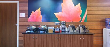 A reception area with a wooden counter, a large painting of leaves, and a sign labeled "KITCHEN".