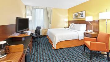 Una habitación de hotel con una cama, un escritorio con computadora, televisor y una silla.