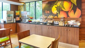 Ein Frühstücksbereich mit einer Theke, Sitzgelegenheiten und einer Wandmalerei mit Früchten.