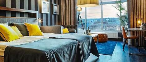 Une chambre d’hôtel avec un grand lit, un bureau, une chaise, une lampe et une vue sur la ville.