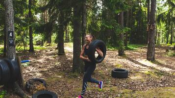 En person som springer genom en skog med träd och utspridda däck på marken.