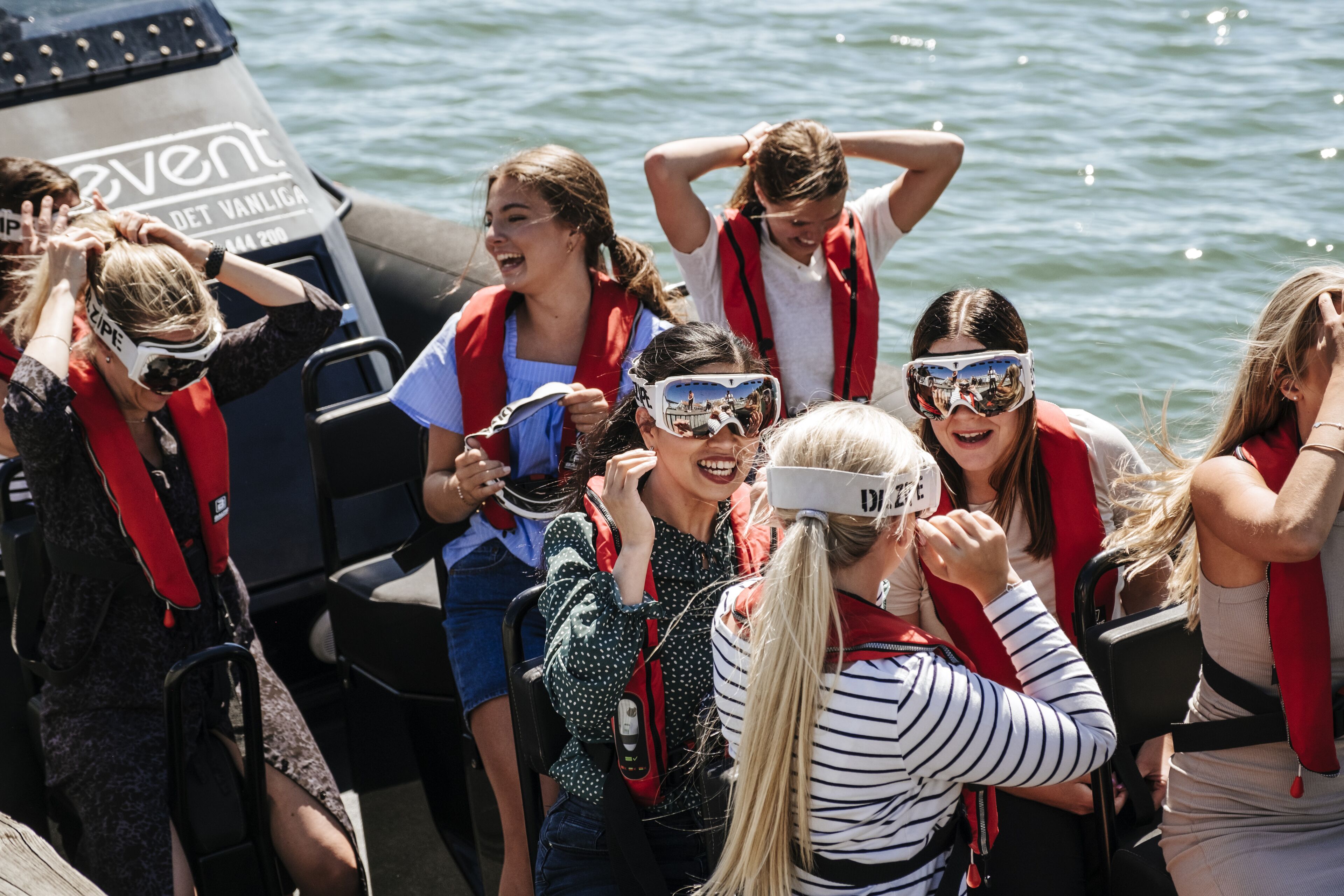Un grupo de personas en un bote, con chalecos salvavidas y gafas, sugiriendo una actividad acuática.