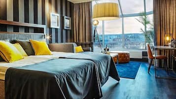 Ett modernt hotellrum med en stor säng, ett skrivbord och utsikt över staden.