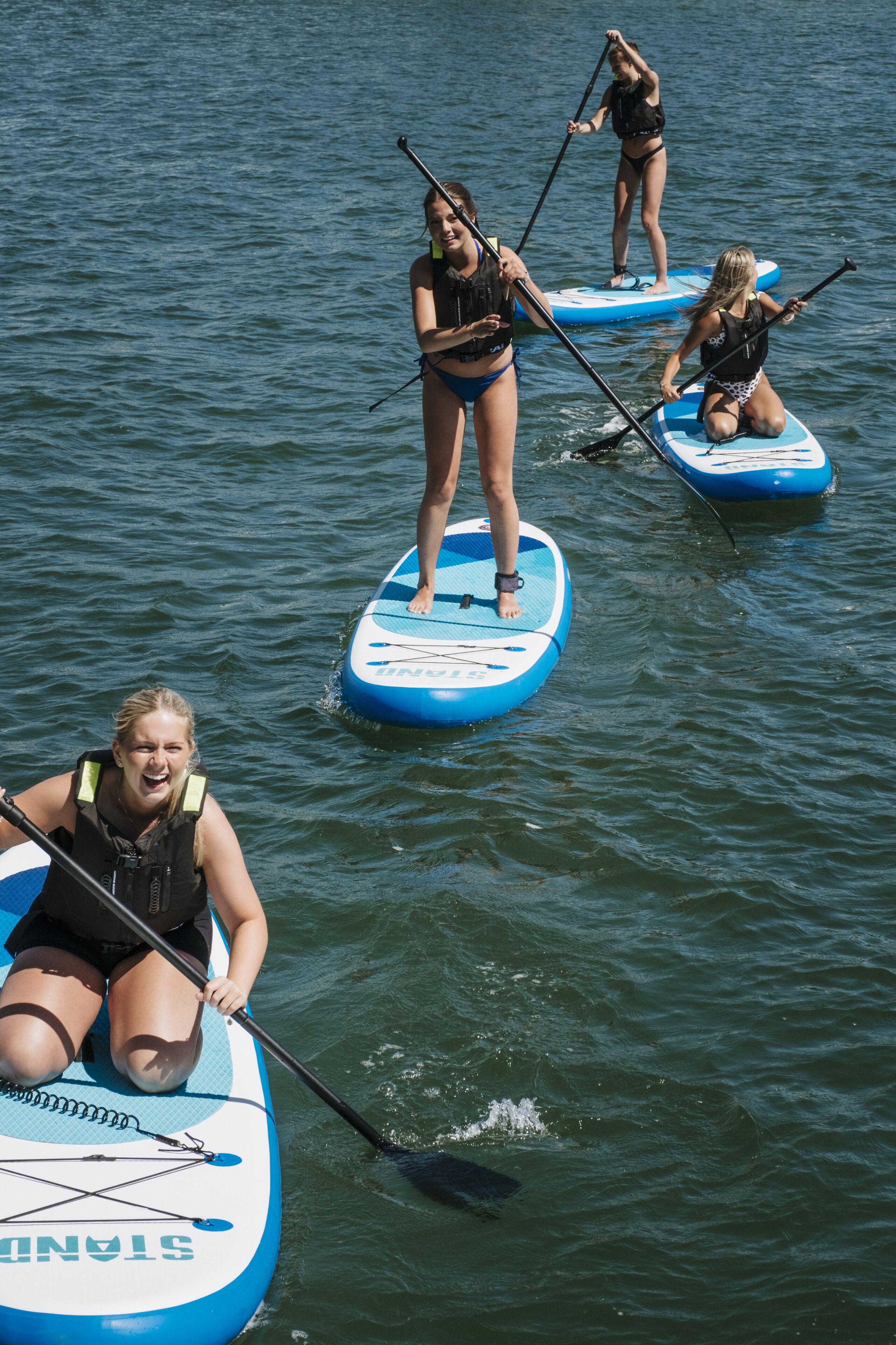 Drie paddleboards op het water, met mensen die erop staan.