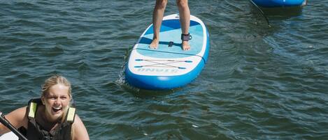 Three paddleboards on water with people standing on them.