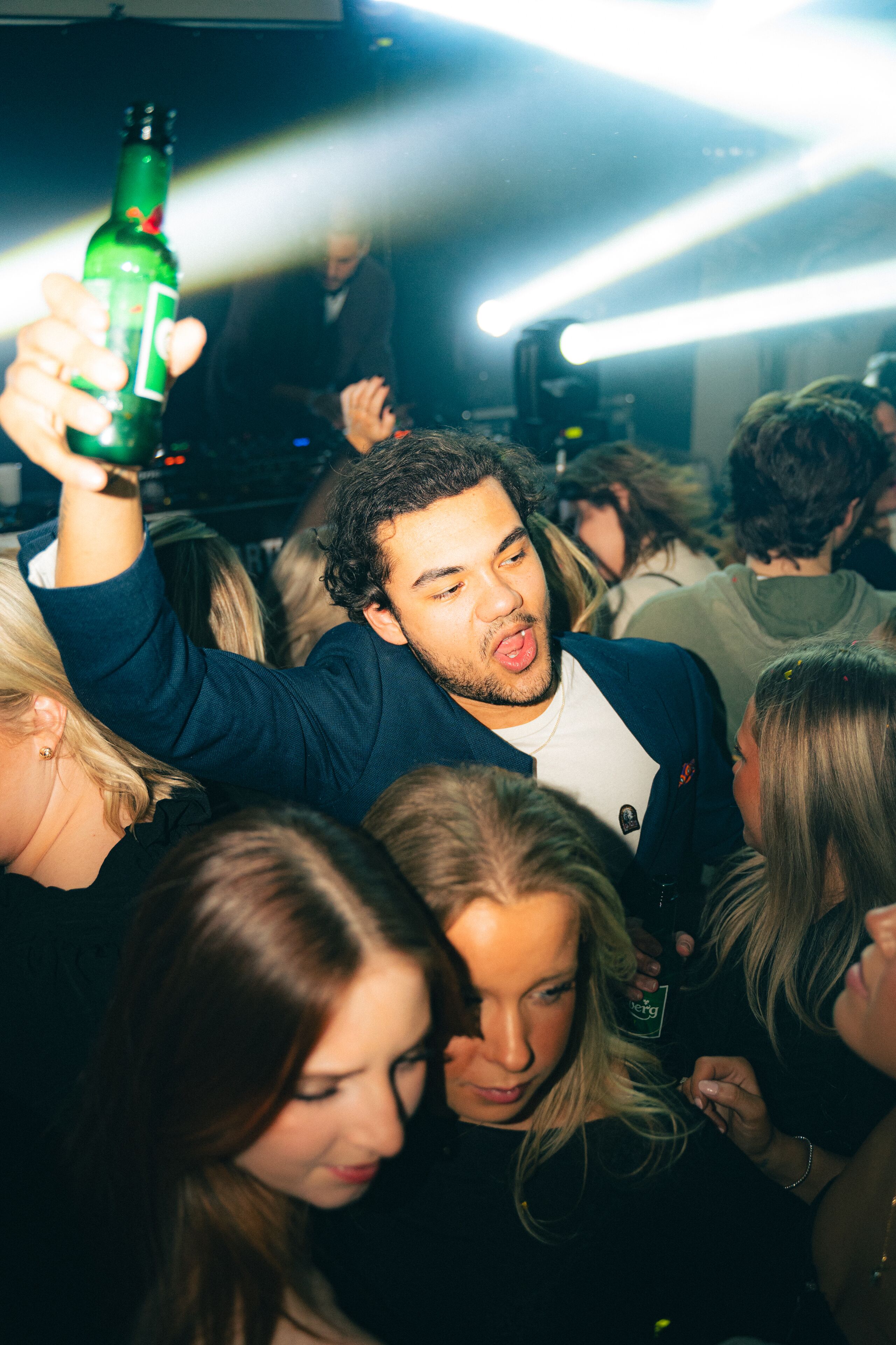 A crowded indoor space with people, some holding bottles.