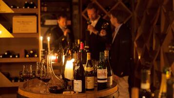 A wine barrel with bottles and glasses, a lit candle, and a sign in a dimly lit room.