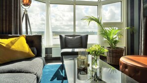 Una sala moderna con sofá, una mesa de centro y vista al mar a través de grandes ventanales.