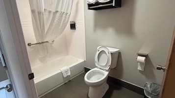 A bathroom with a bathtub, toilet, and a shelf with towels.