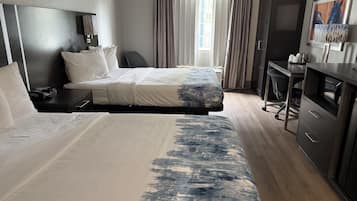 A hotel room with a bed, a desk, a chair, a TV, and a painting on the wall.