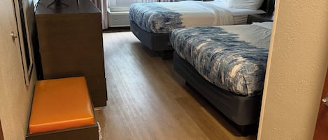 A hotel room with a bed, a desk, a chair, and a small seating area.