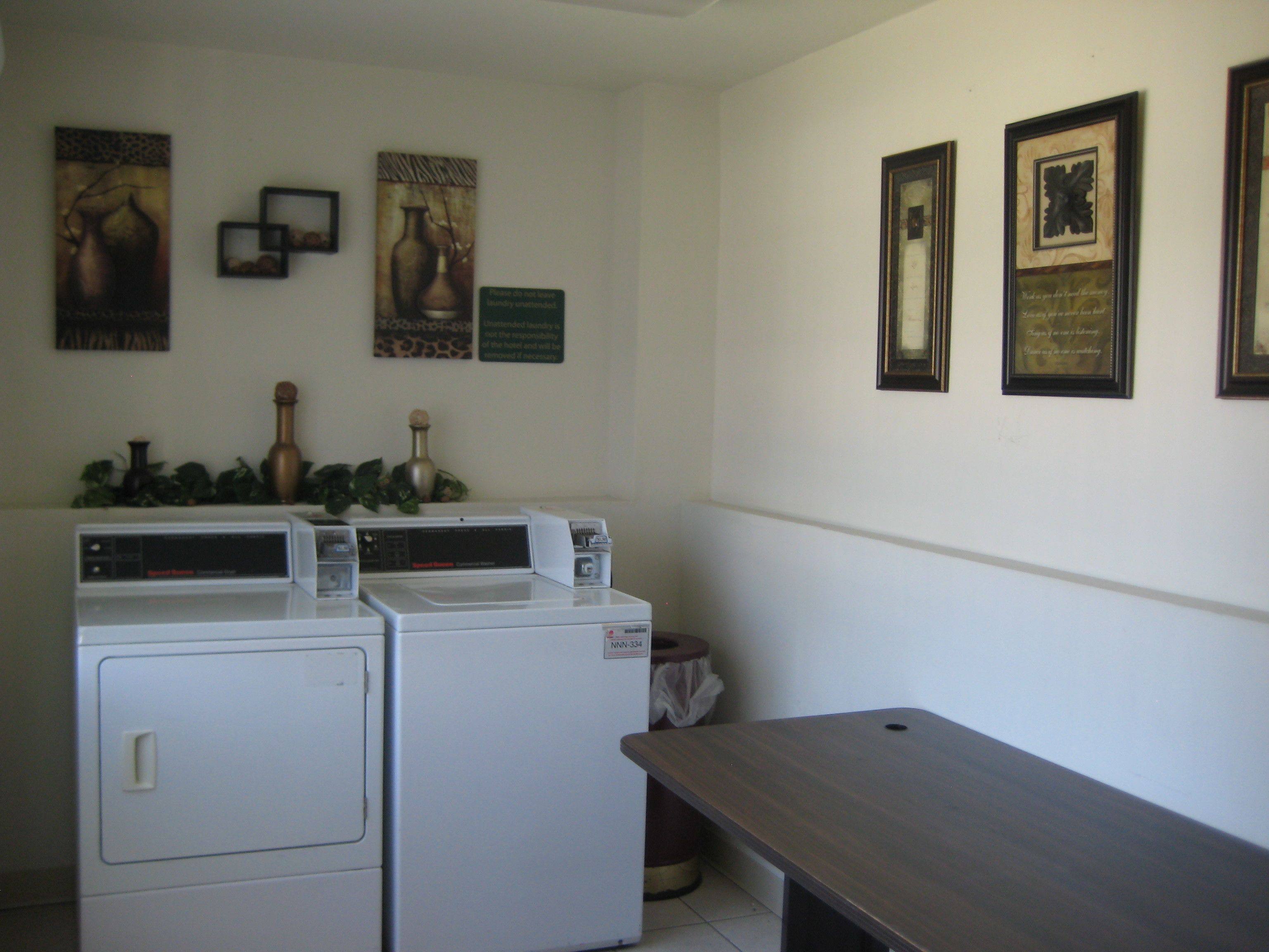 Un cuarto de lavandería con dos lavadoras, una mesa de madera y varias fotografías enmarcadas en la pared.