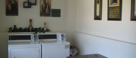 Un cuarto de lavandería con dos lavadoras, una mesa de madera y varias fotografías enmarcadas en la pared.