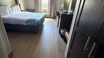 A hotel room with a bed, a desk, a television, and a wardrobe.