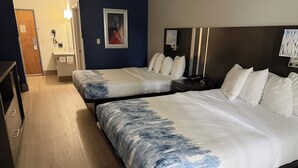 Quarto de hotel com duas camas, banheiro e corredor.