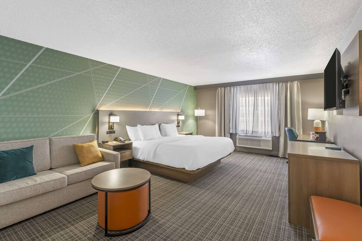 A hotel room with a bed, a sofa, a desk, and a round table.
