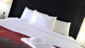 A neatly made bed with white linens and a red patterned bedspread.