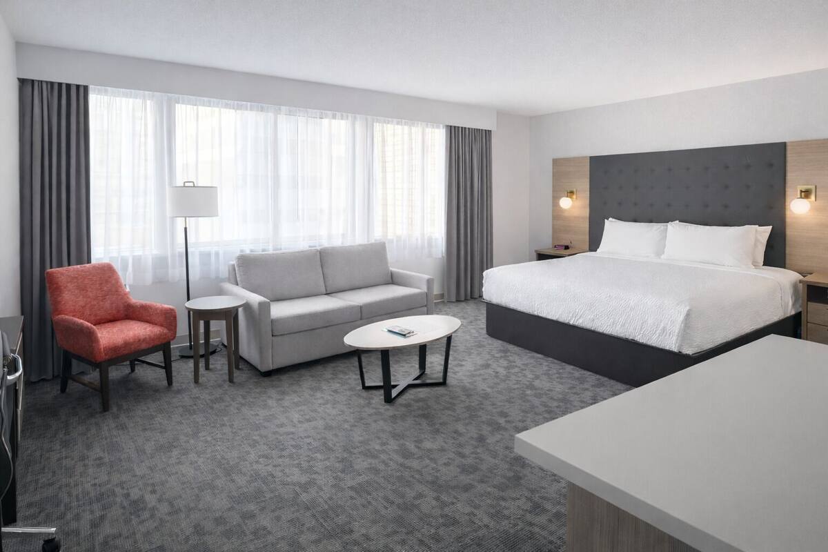 Une chambre d’hôtel comprenant un lit, un canapé, une chaise, une petite table et un bureau.