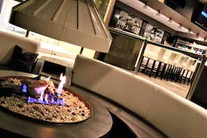 A bar area with a fireplace, seating, and a bar stocked with bottles.