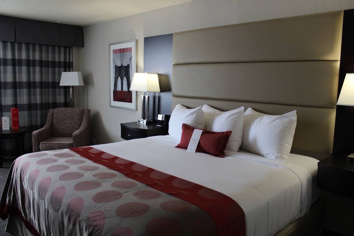 Une chambre d’hôtel avec un grand lit, une chaise, une table de chevet et une lampe.
