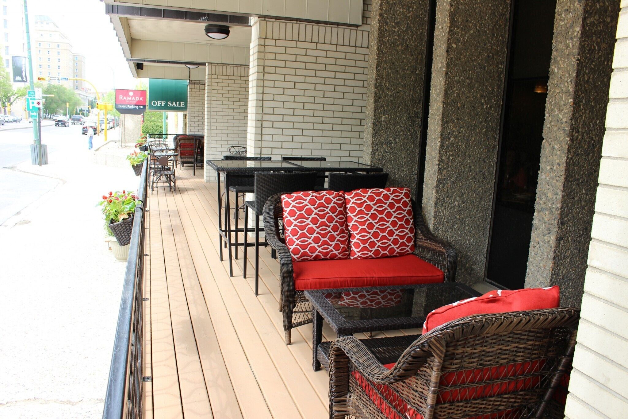 An outdoor seating area with wicker furniture and red cushions, a brick wall, and a sign indicating a sale.