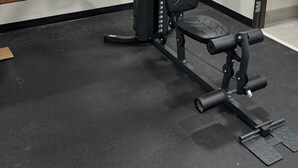 Een sportschool met een halterbank, een squatsysteem en een pull-up stang.
