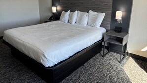Een hotelkamer met een groot bed, twee nachtkastjes, een wandlamp en een digitale klok.