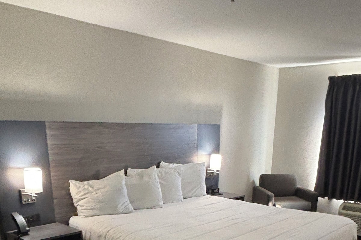 A hotel room with a large bed, two bedside tables, a chair, and a nightstand.