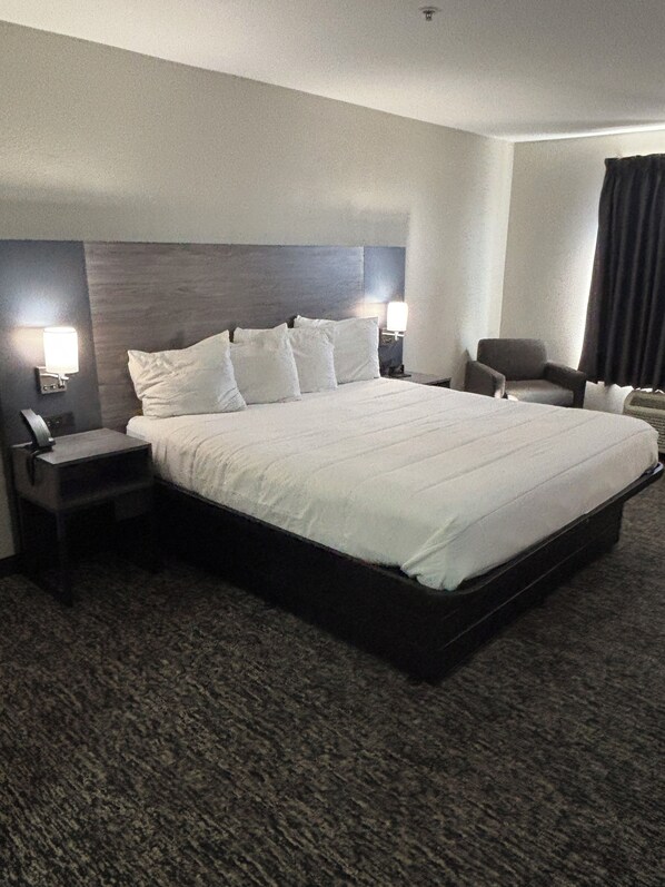 A hotel room with a large bed, two bedside tables, a chair, and a nightstand. - Sonesta Essential Augusta (Augusta)