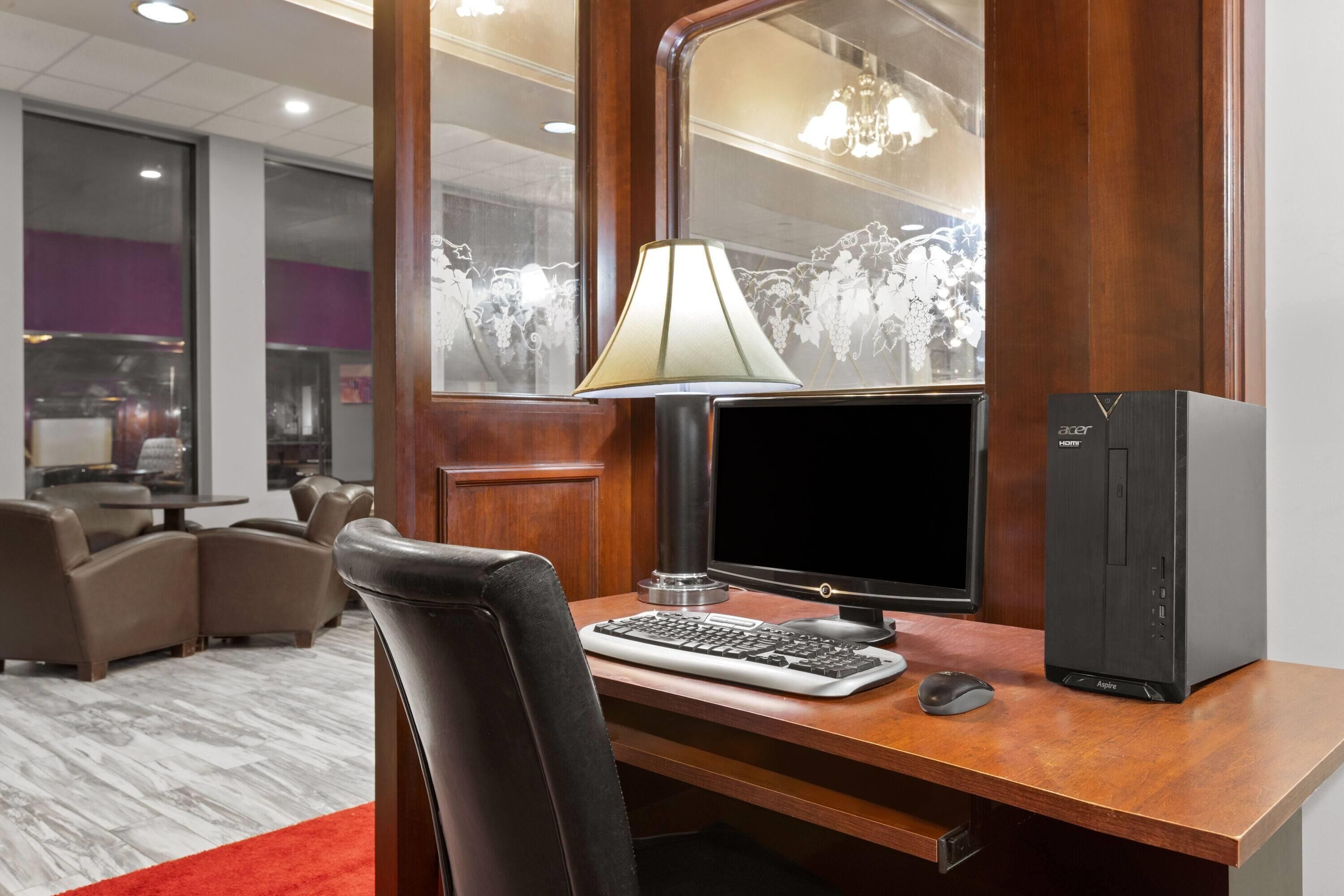 Ein Hotelzimmer mit einem Holztisch, einem Computer, einer Lampe und einem Stuhl.