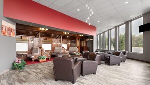 A spacious lobby with a red accent wall, large windows, and a mix of modern and classic furniture.