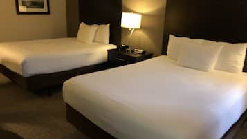 Two single beds with white linens, a nightstand with a lamp, and a framed picture on the wall.