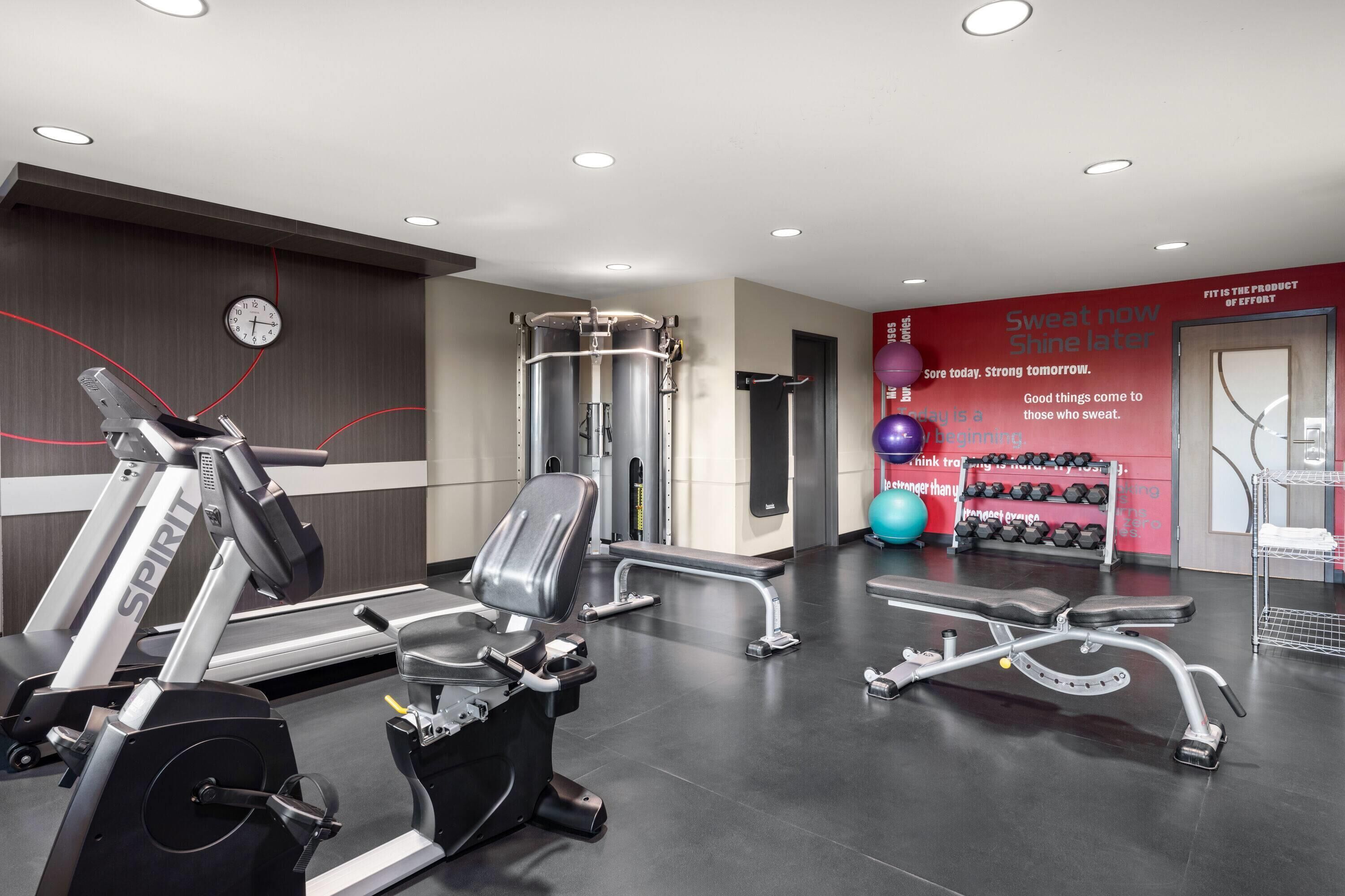 Un gimnasio moderno con equipo de cardio, máquinas de pesas y un reloj de pared.