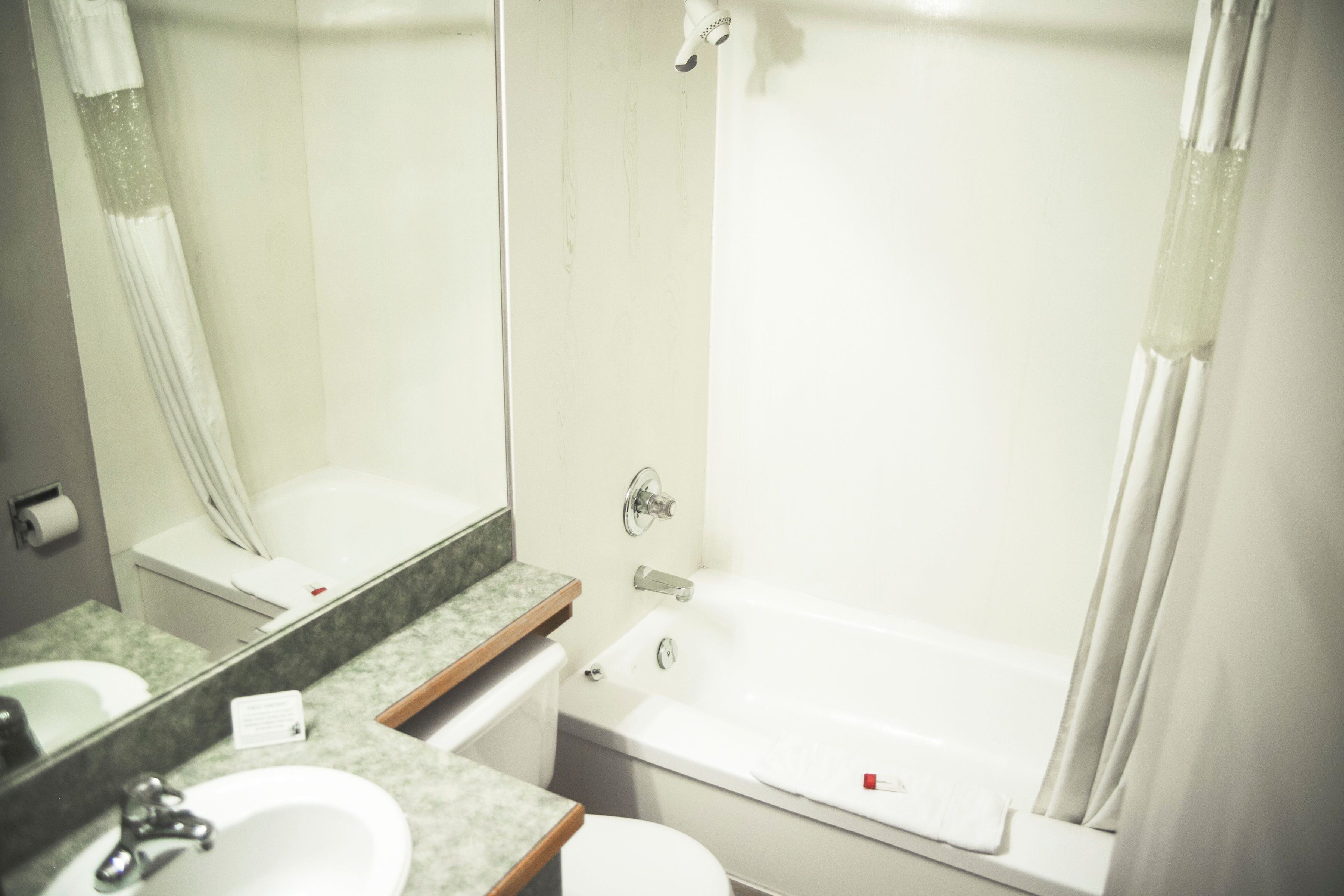 Un baño con lavamanos, espejo, inodoro y bañera.