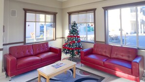 A spacious lobby with two red leather sofas, a coffee table, and a Christmas tree. - Ramada by Wyndham Quesnel (Quesnel)