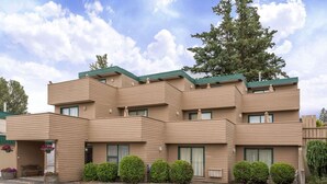 A multi-story hotel with a modern design, featuring a flat roof, large windows, and a parking lot in front. - Ramada by Wyndham Quesnel (Quesnel)