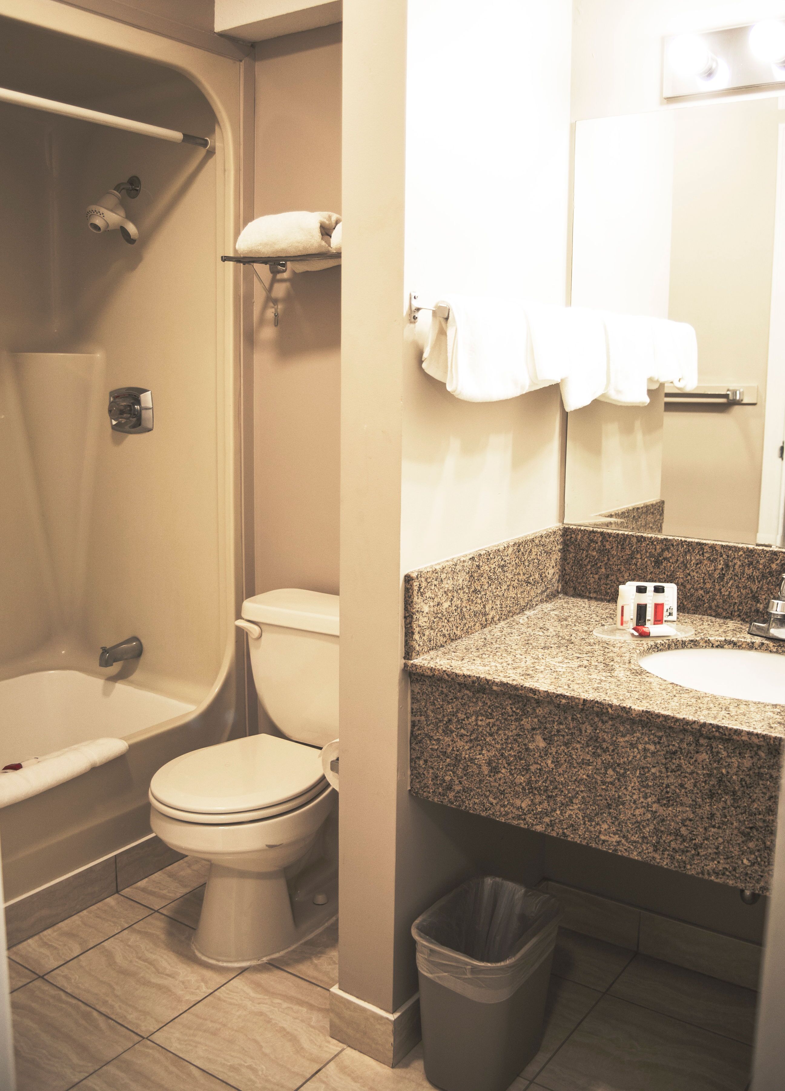 A bathroom with a bathtub, toilet, sink, and a trash bin.