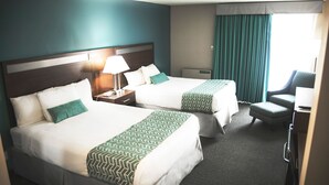 A hotel room with two beds, a desk, a chair, and a window with curtains. - Ramada by Wyndham Quesnel (Quesnel)