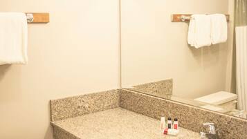 A bathroom with a granite countertop sink, a mirror, and a toilet.