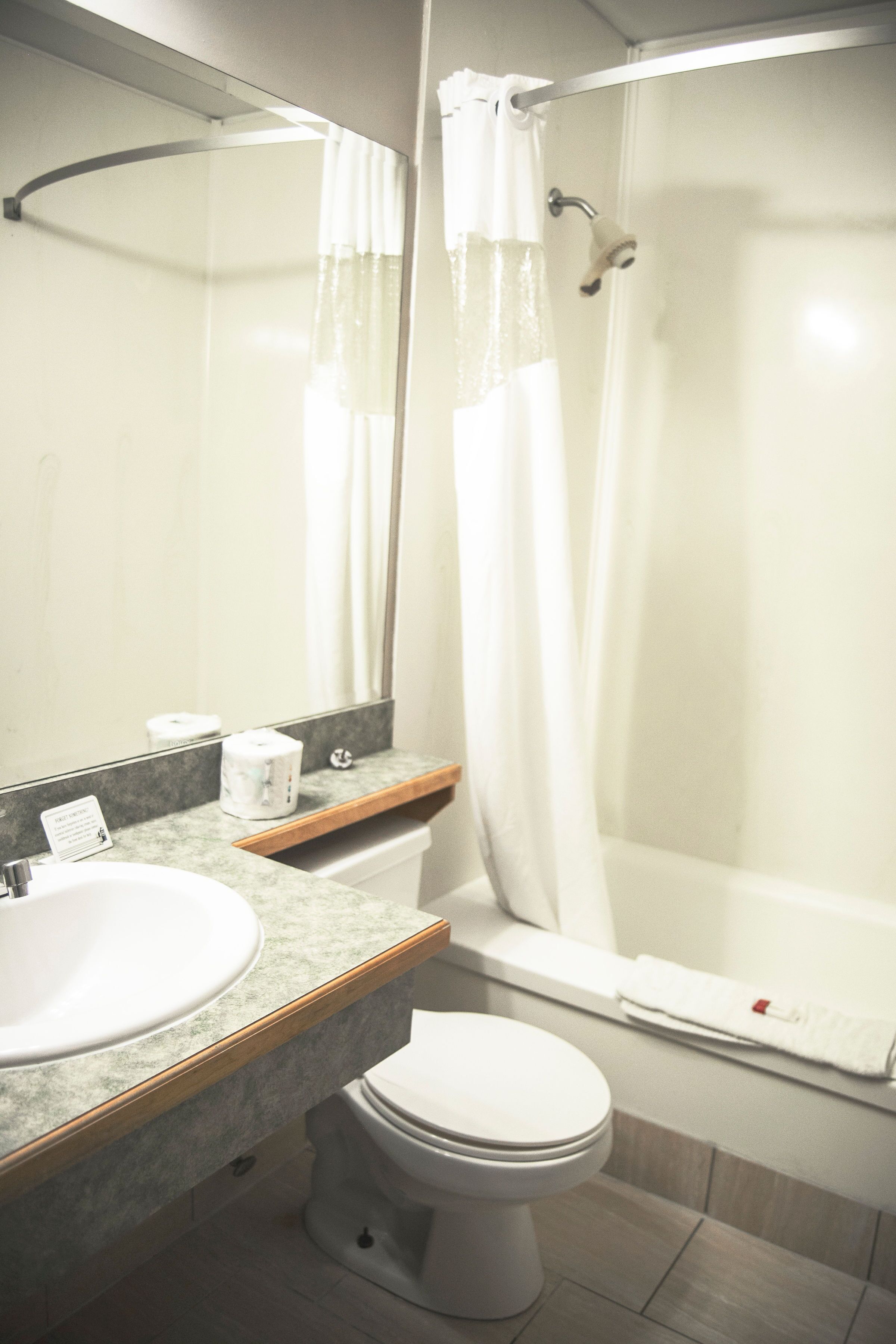 Baño con lavamanos blanco, inodoro y ducha con puerta de vidrio.