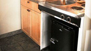 A compact kitchen with wooden cabinets, a stainless steel stove, a microwave, and a coffee maker. - Ramada by Wyndham Quesnel (Quesnel)