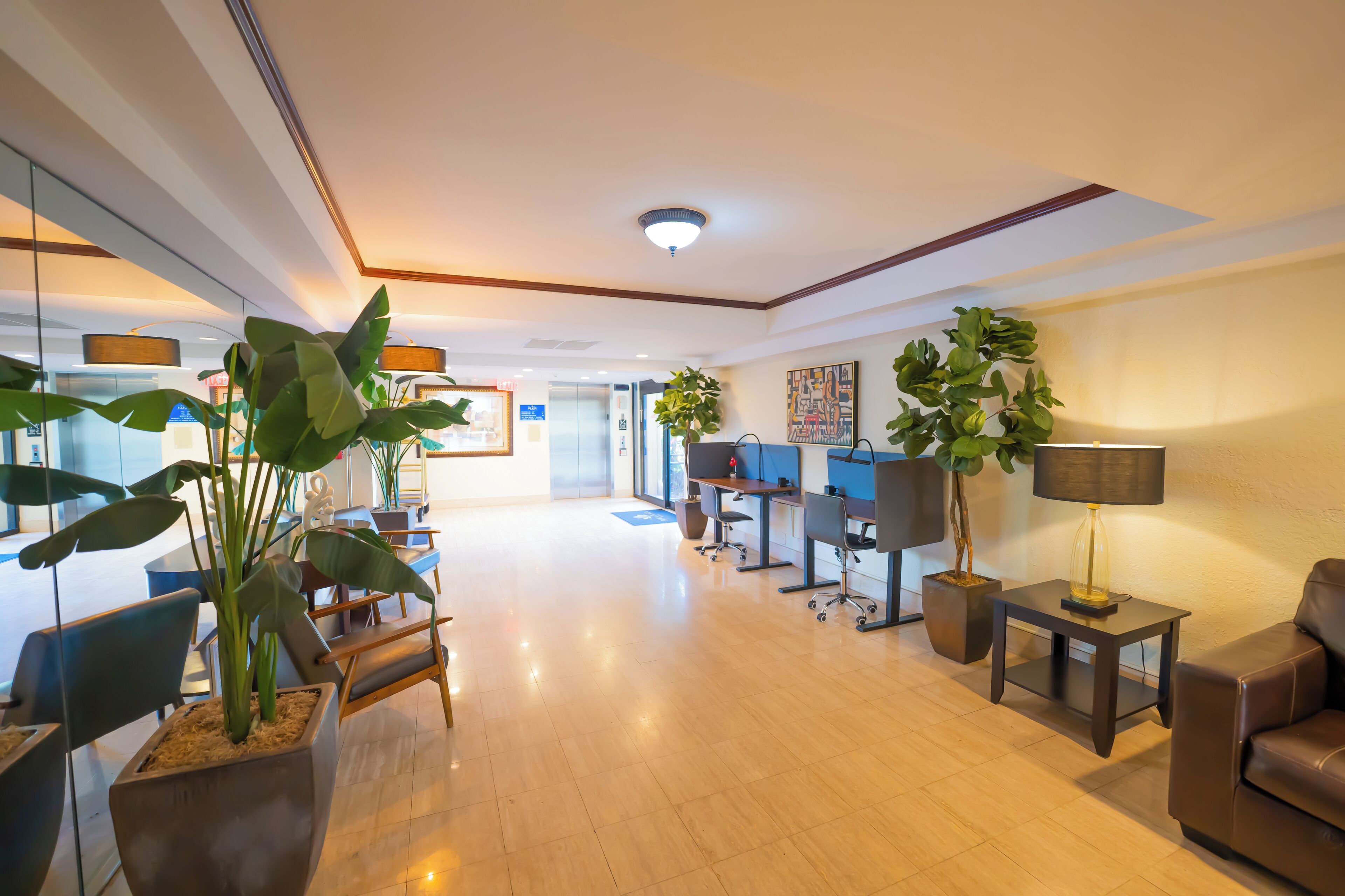 Eine großzügige Lobby mit Rezeption, mehreren Sitzgelegenheiten, einer Couch und Topfpflanzen.