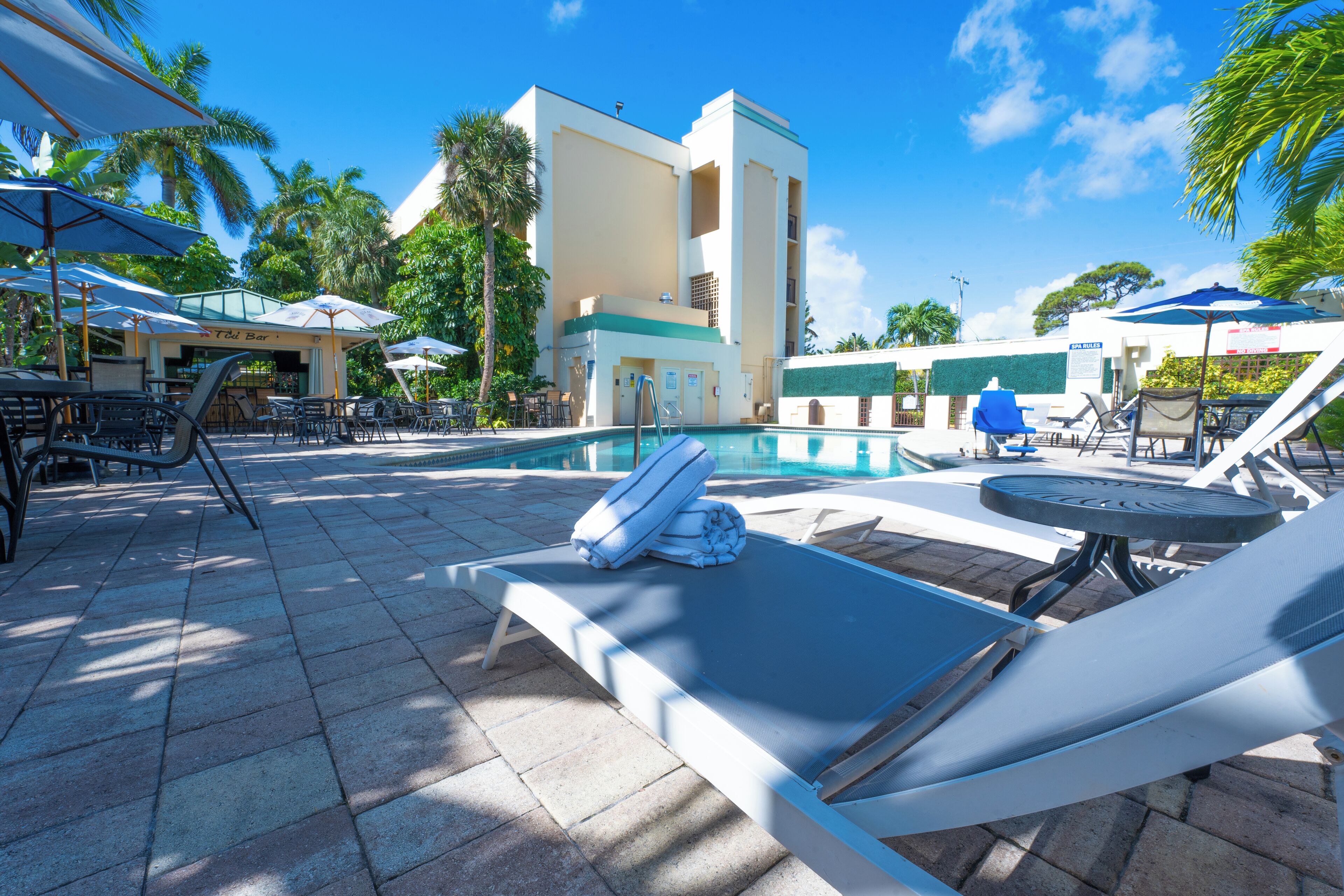 Un área junto a la piscina con sillones de descanso, sombrillas y un bar.
