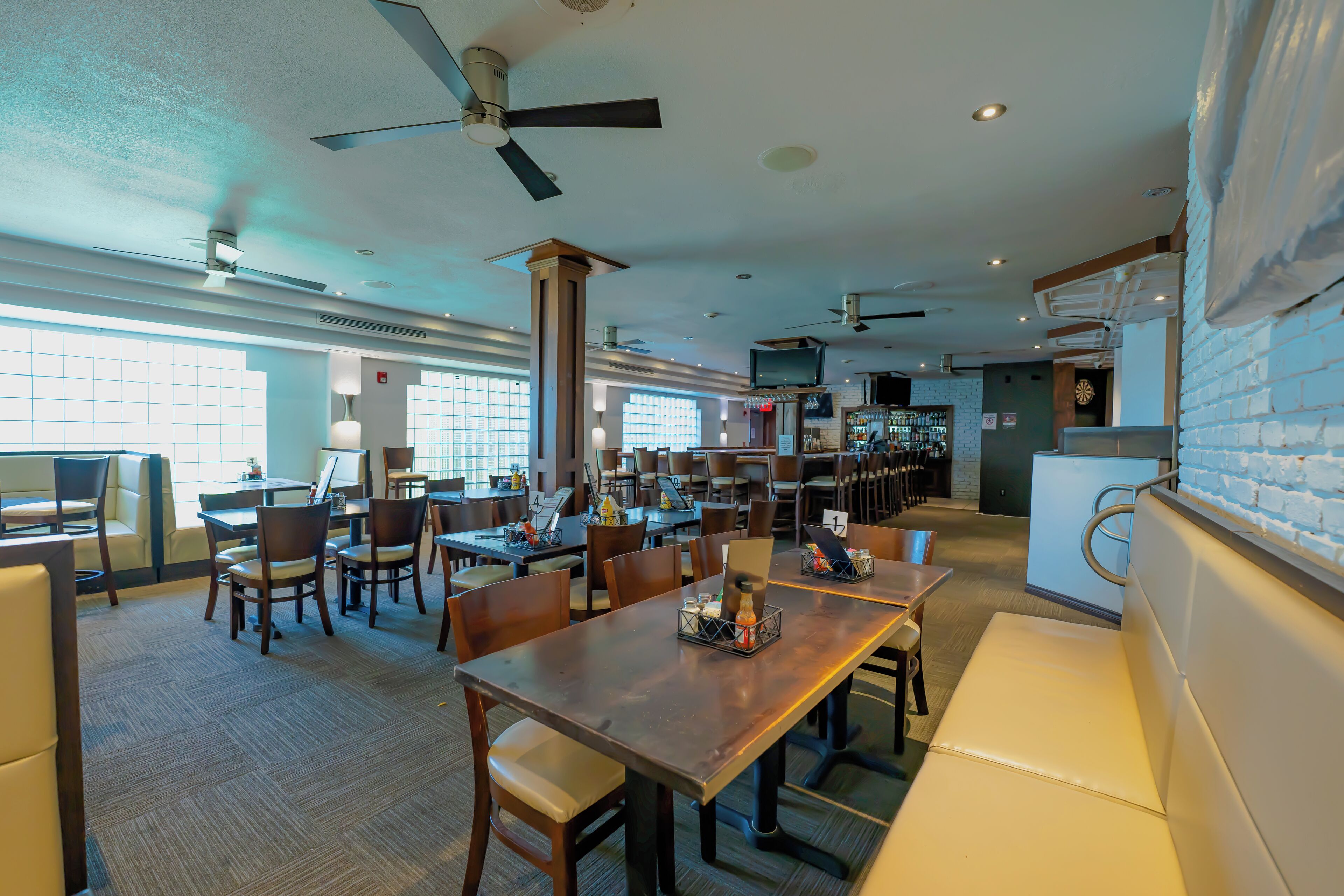 Un espaiós restaurant amb sostres alts, moltes taules i caires, i una zona de bar.