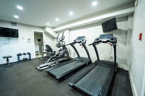 Un gimnasio con cintas de correr, una bicicleta estática y mancuernas.