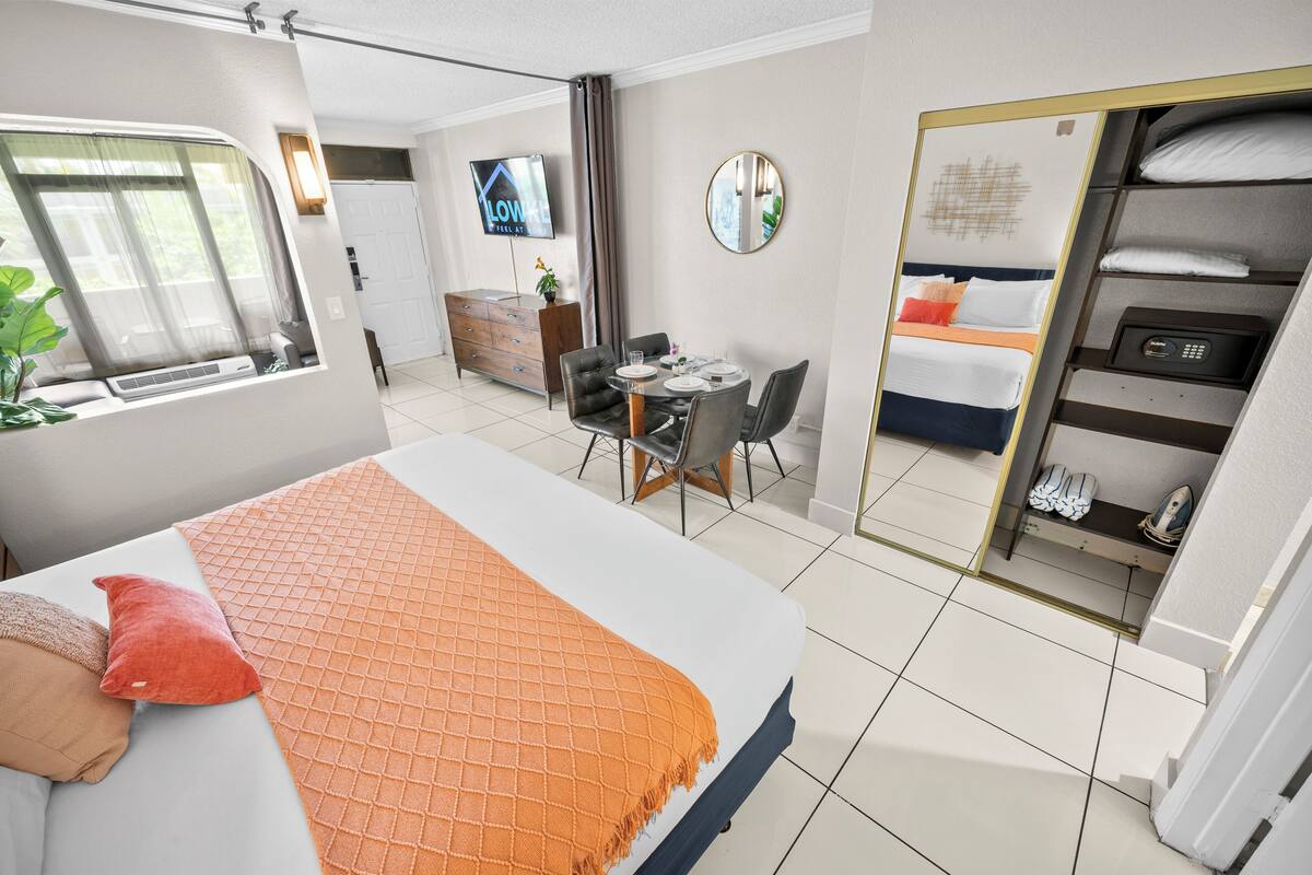 A hotel room with a bed, a desk, a chair, a TV, and a wardrobe.
