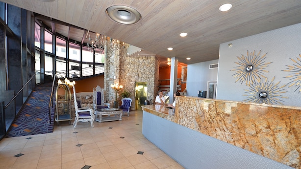A lobby with a reception desk, a staircase, and a seating area with a patterned carpet.