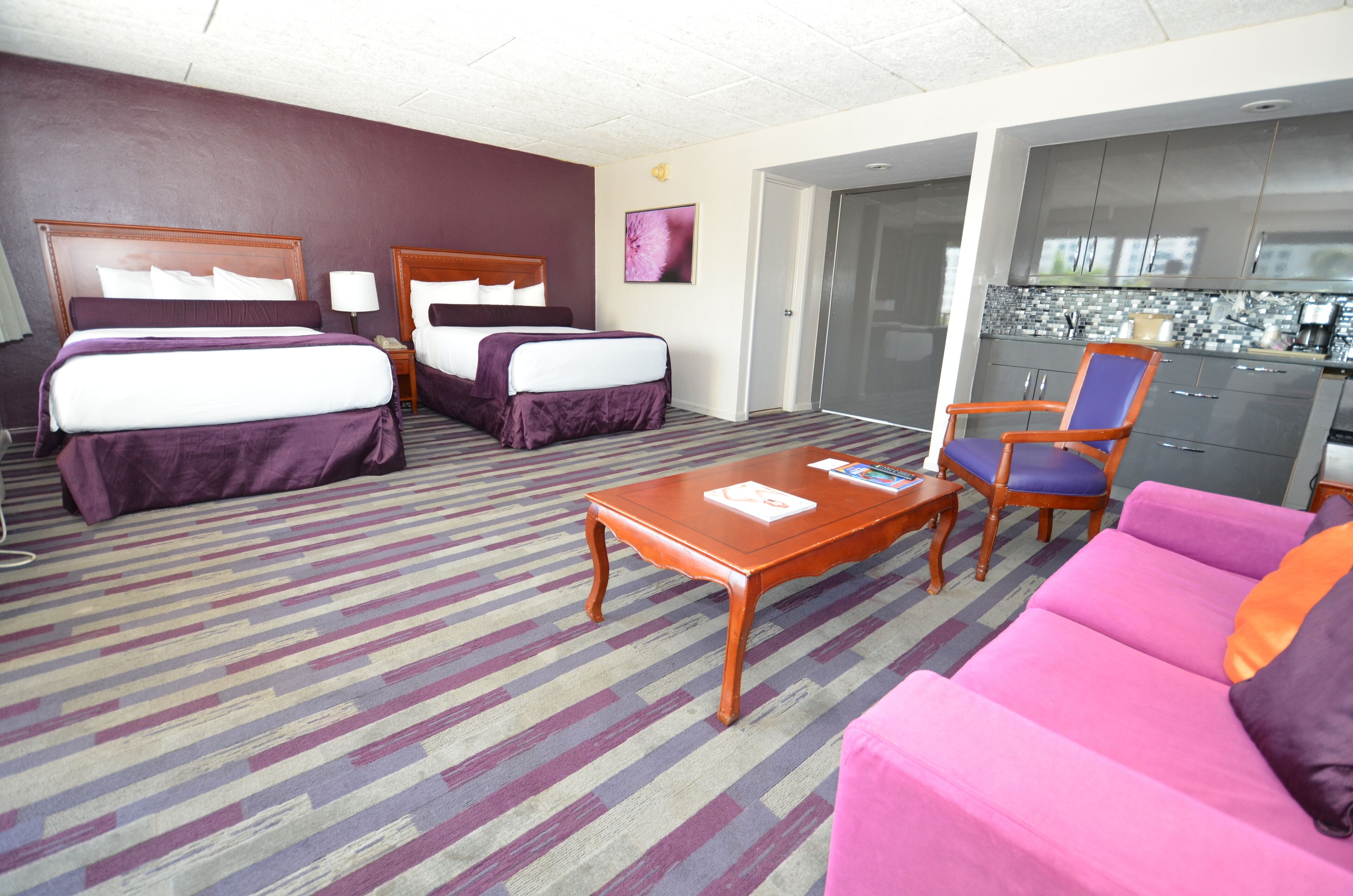 Una habitación de hotel con dos camas, un sofá, una mesa de centro y una kitchenette.