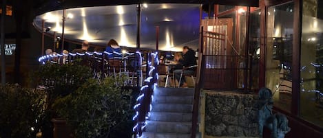 Un restaurante con terraza, una escalera de piedra y una estatua.
